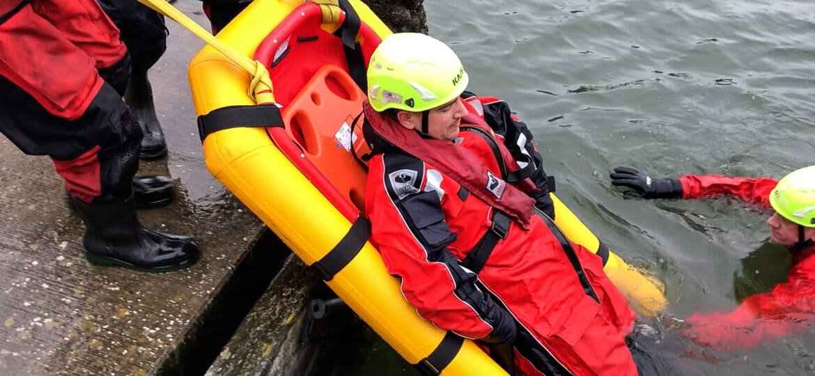 A plastic basket stretcher being used in a water rescue training