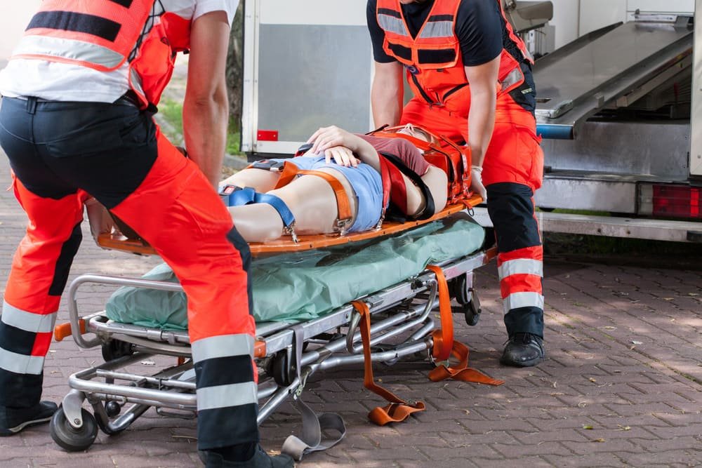 A paramedic effortlessly raising a stretcher using a hydraulic lift system