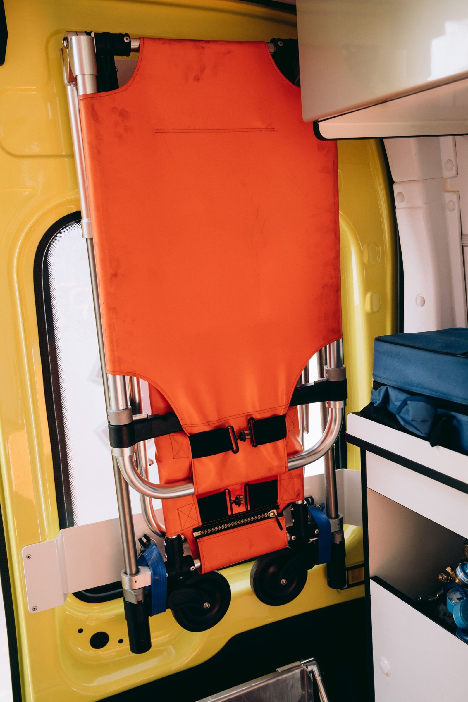 A folded emergency stretcher leaning against a wall in a clean environment