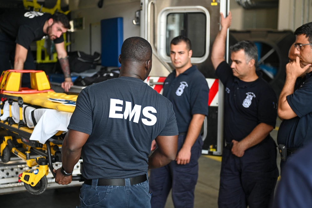 EMS professional removing a wheeled stretcher from an ambulance during training