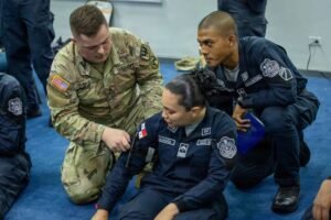 U.S. Army instructor guides a Panamanian police cadet through one-handed tourniquet application during first aid training.