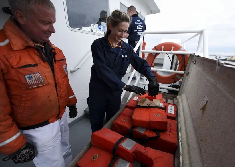 `Marine safety inspector checking life jackets in a vessel’s deck storage locker before use`
